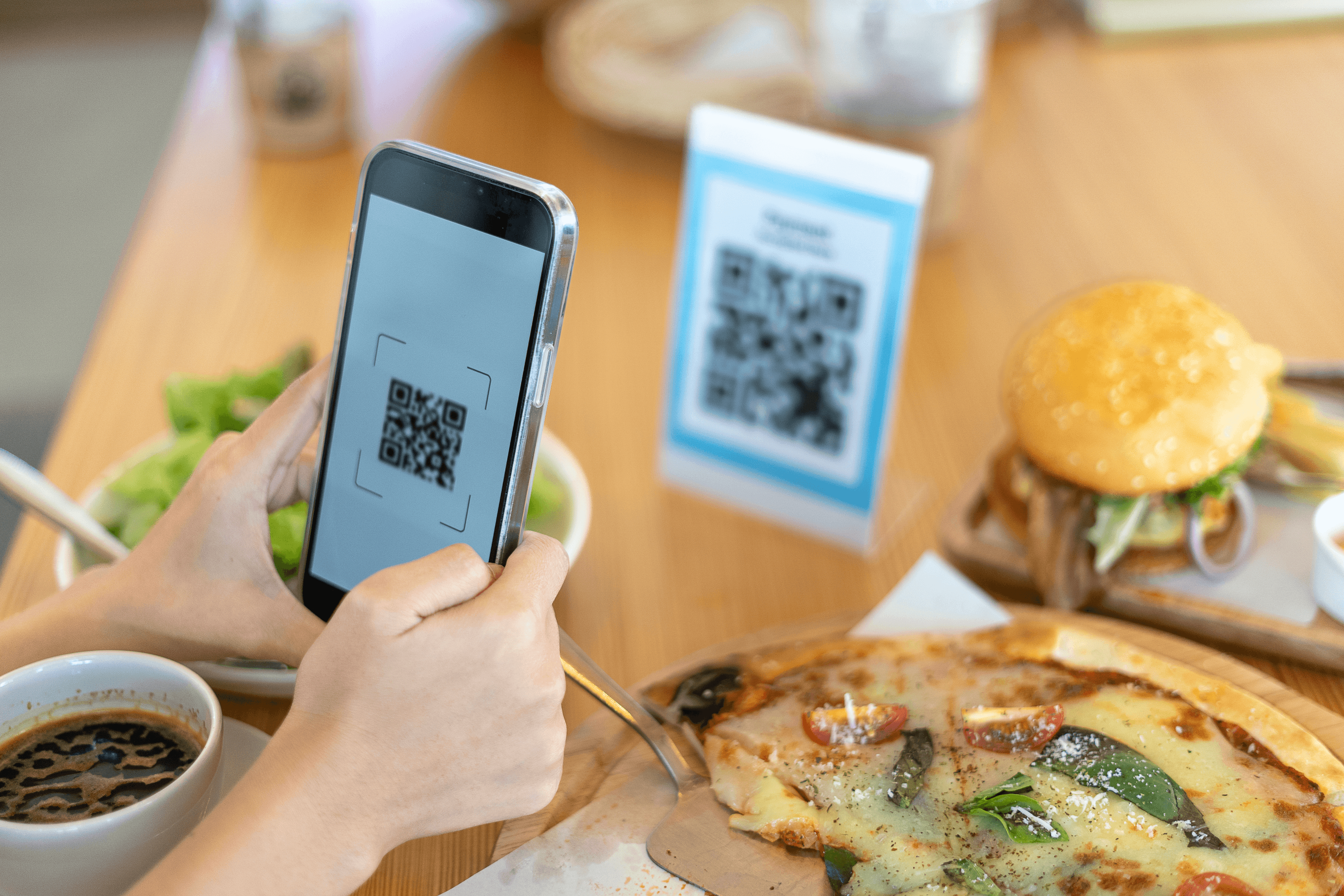 Customer scanning QR code at restaurant table with food